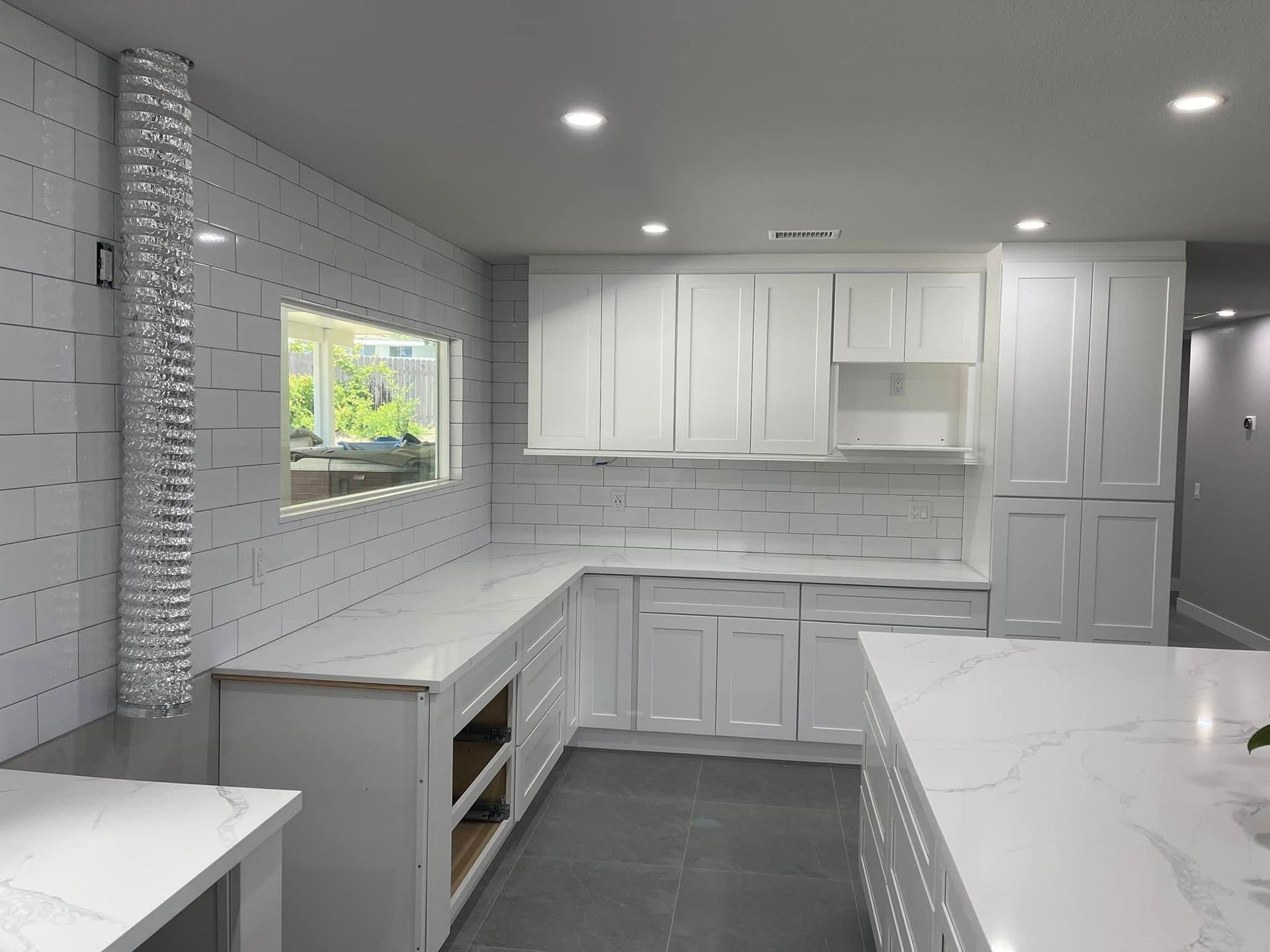 White kitchen with countertop and cabinets, window with outdoor view, and a large island.