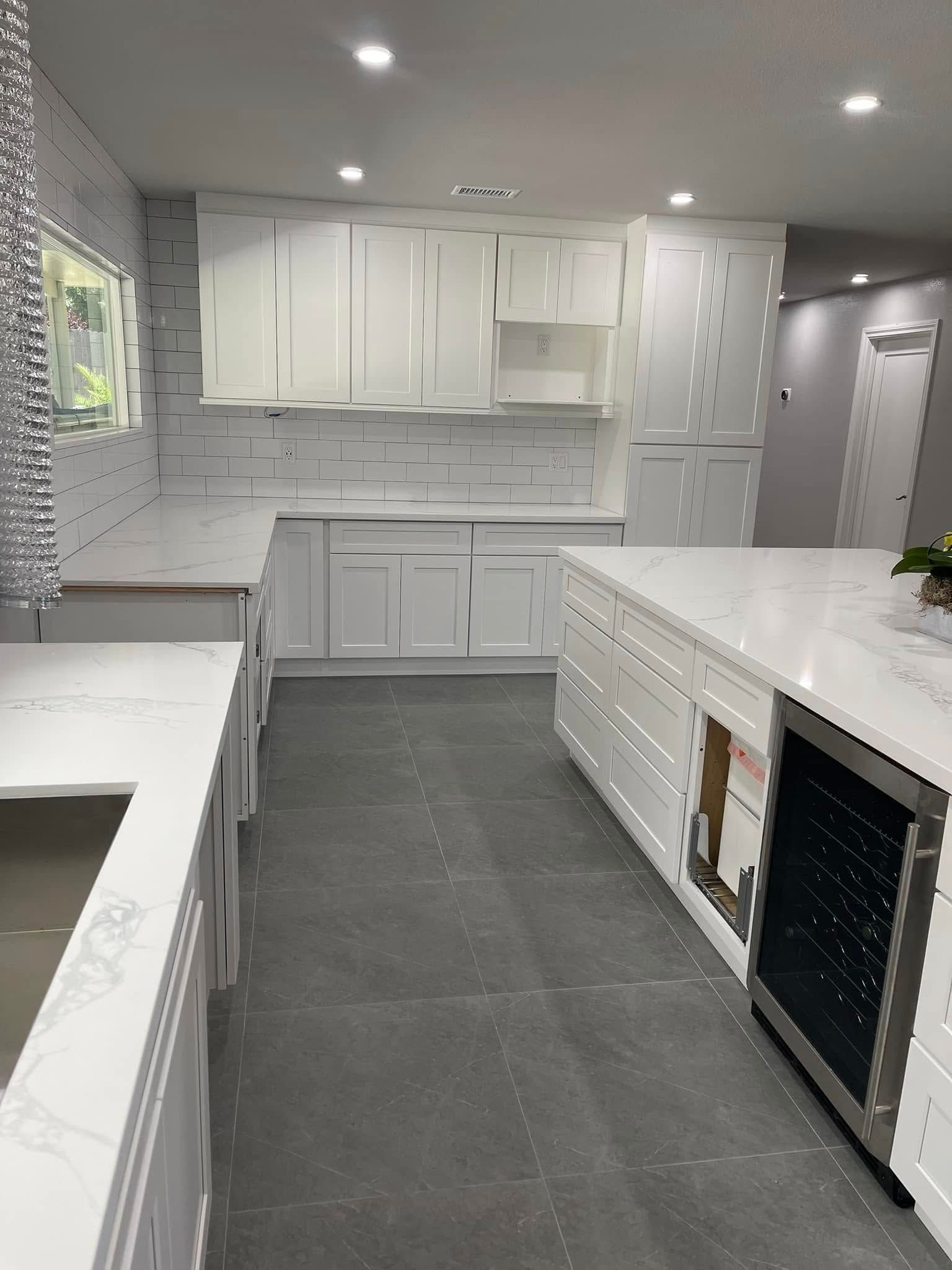 Modern white kitchen with gray floor, countertops, cabinets, and island.