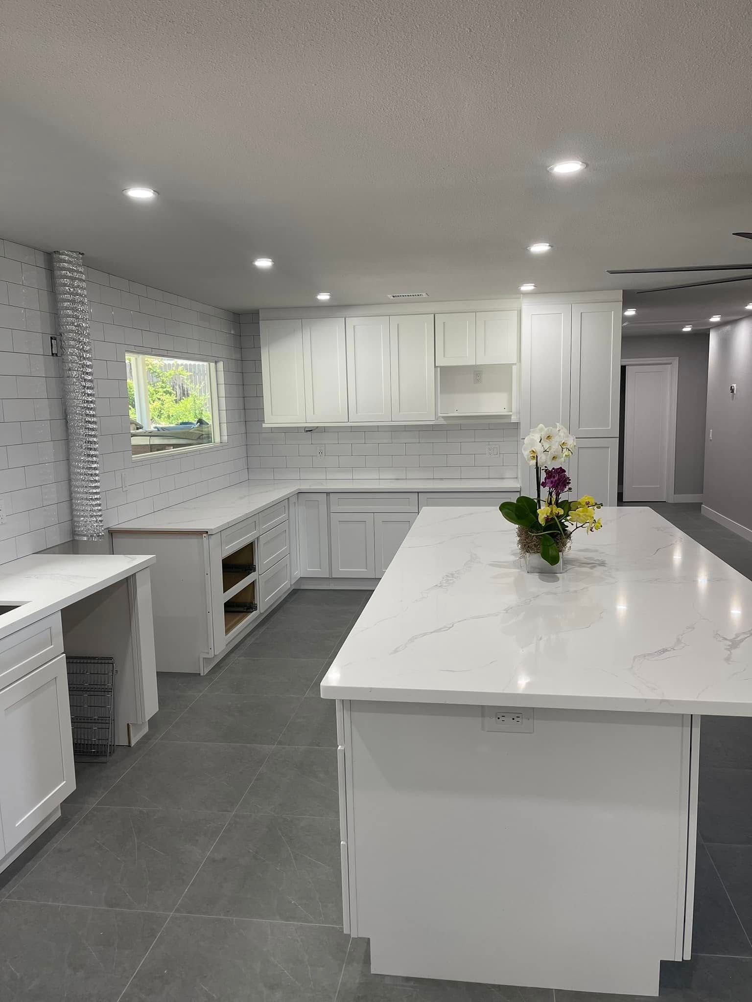White kitchen remodel with quartz countertops, white cabinets, and a large island.