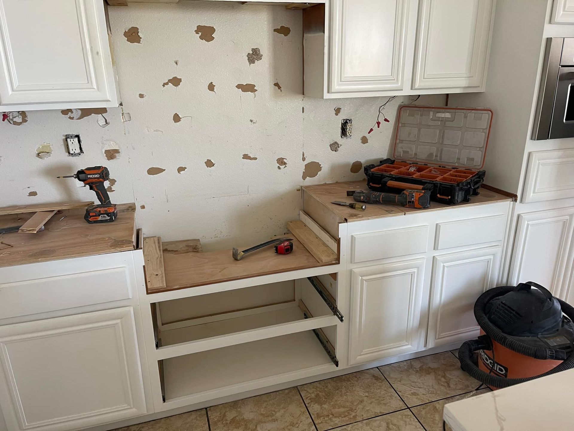 Kitchen renovation: cabinets, exposed wall, tools, and a partially built countertop.
