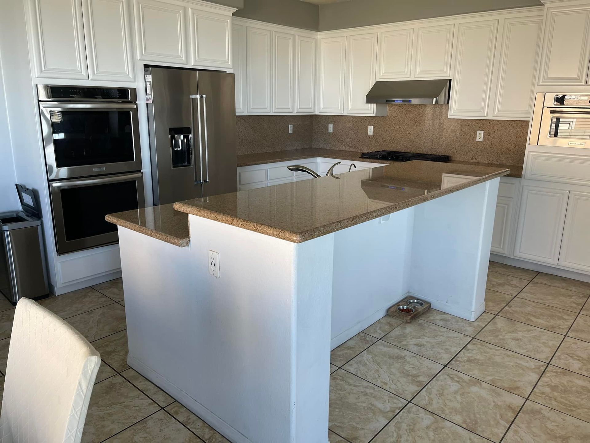 White kitchen with granite countertops and stainless steel appliances.