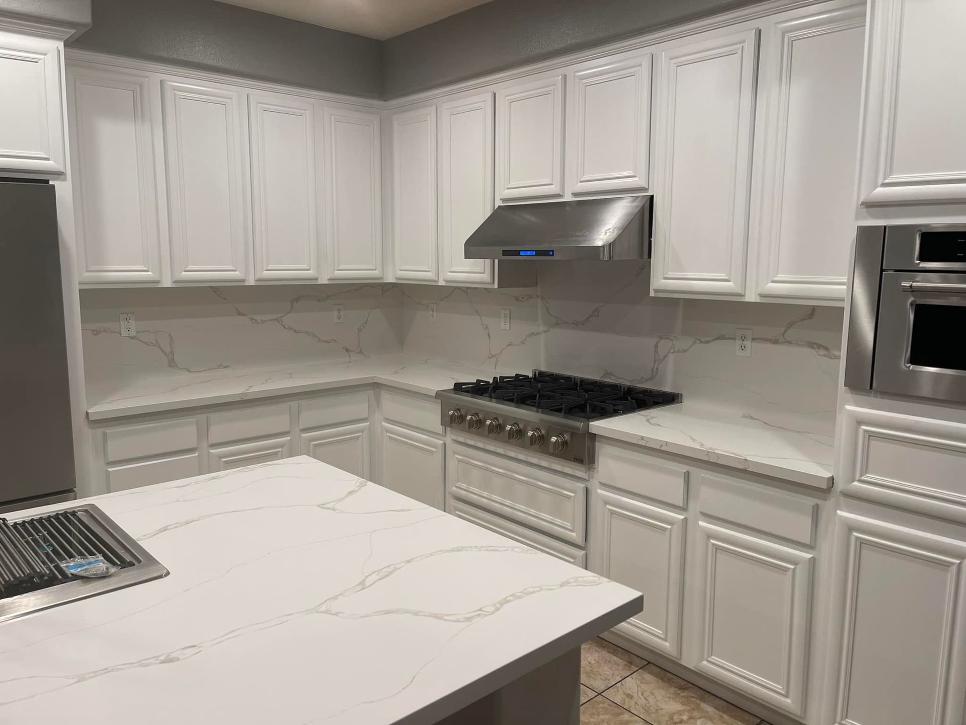 White kitchen with cabinets, countertops, stainless steel appliances, and gas range.