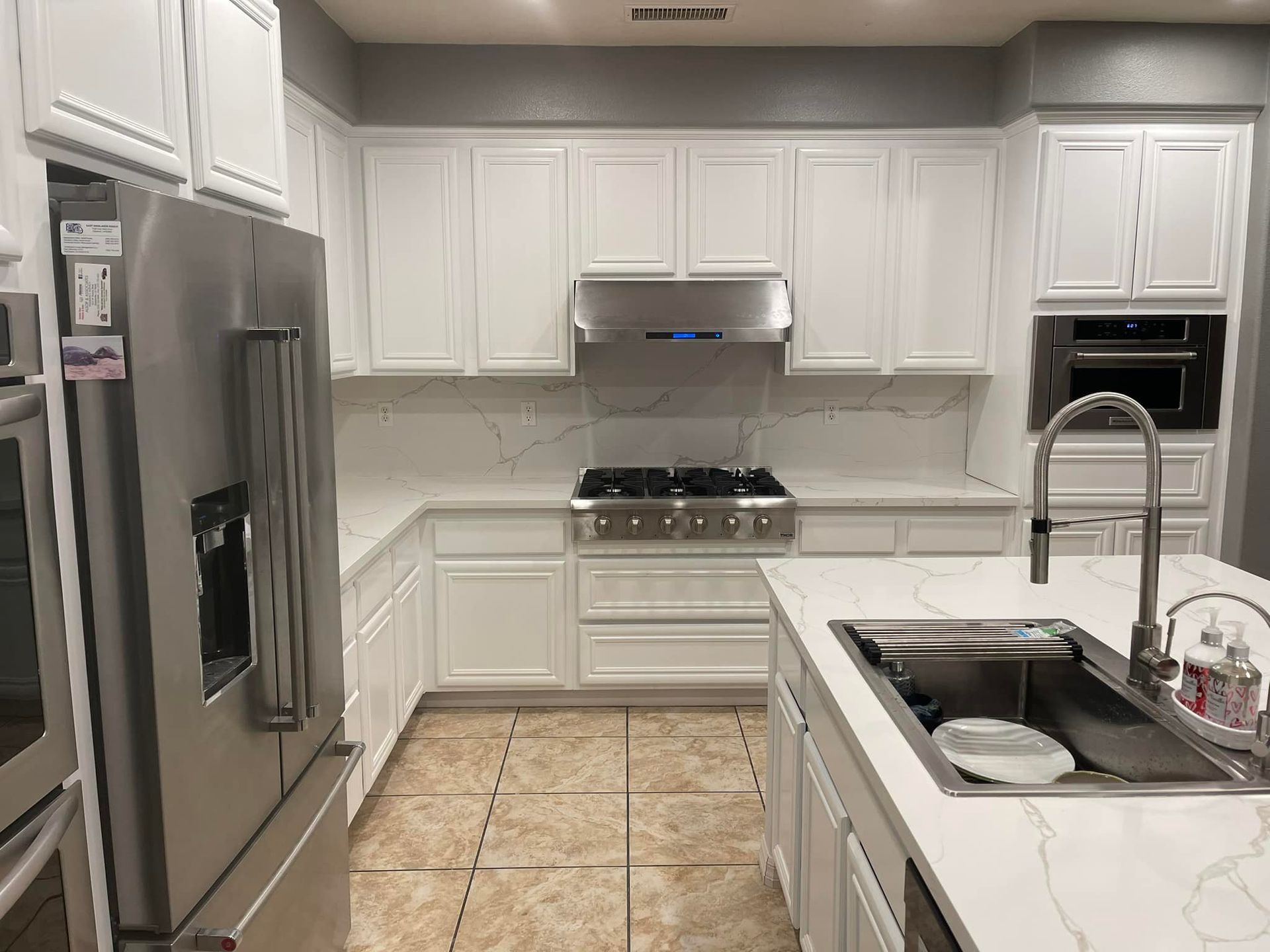 White kitchen with stainless steel appliances and a large island.