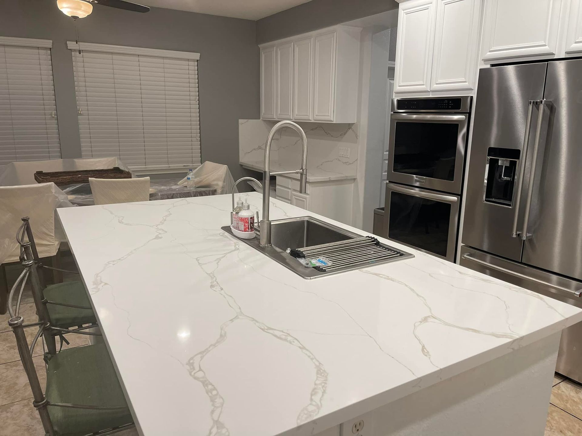 Modern kitchen with white cabinets, quartz countertops, stainless steel appliances, and a sink.