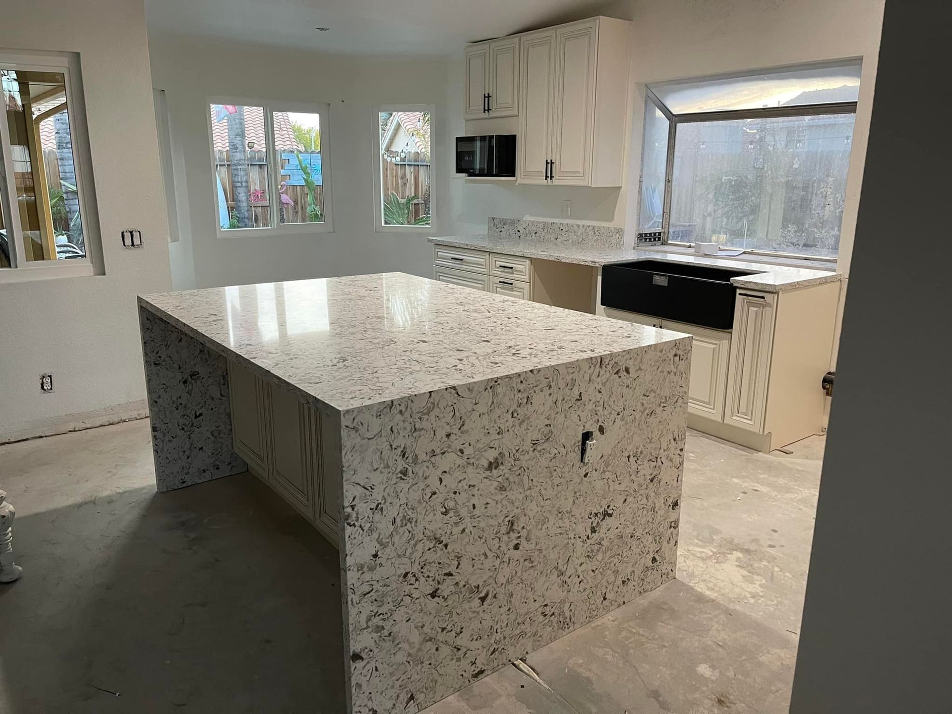 Kitchen with white cabinets, speckled countertops, and a large island.