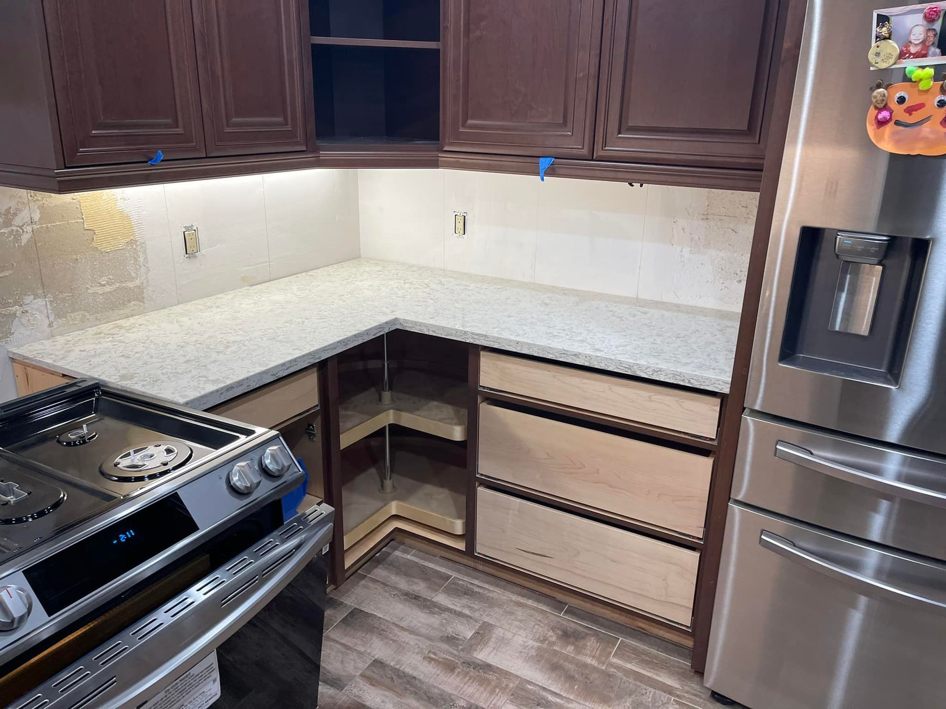 Kitchen remodel: granite countertop, brown cabinets, stainless steel appliances, and new backsplash.