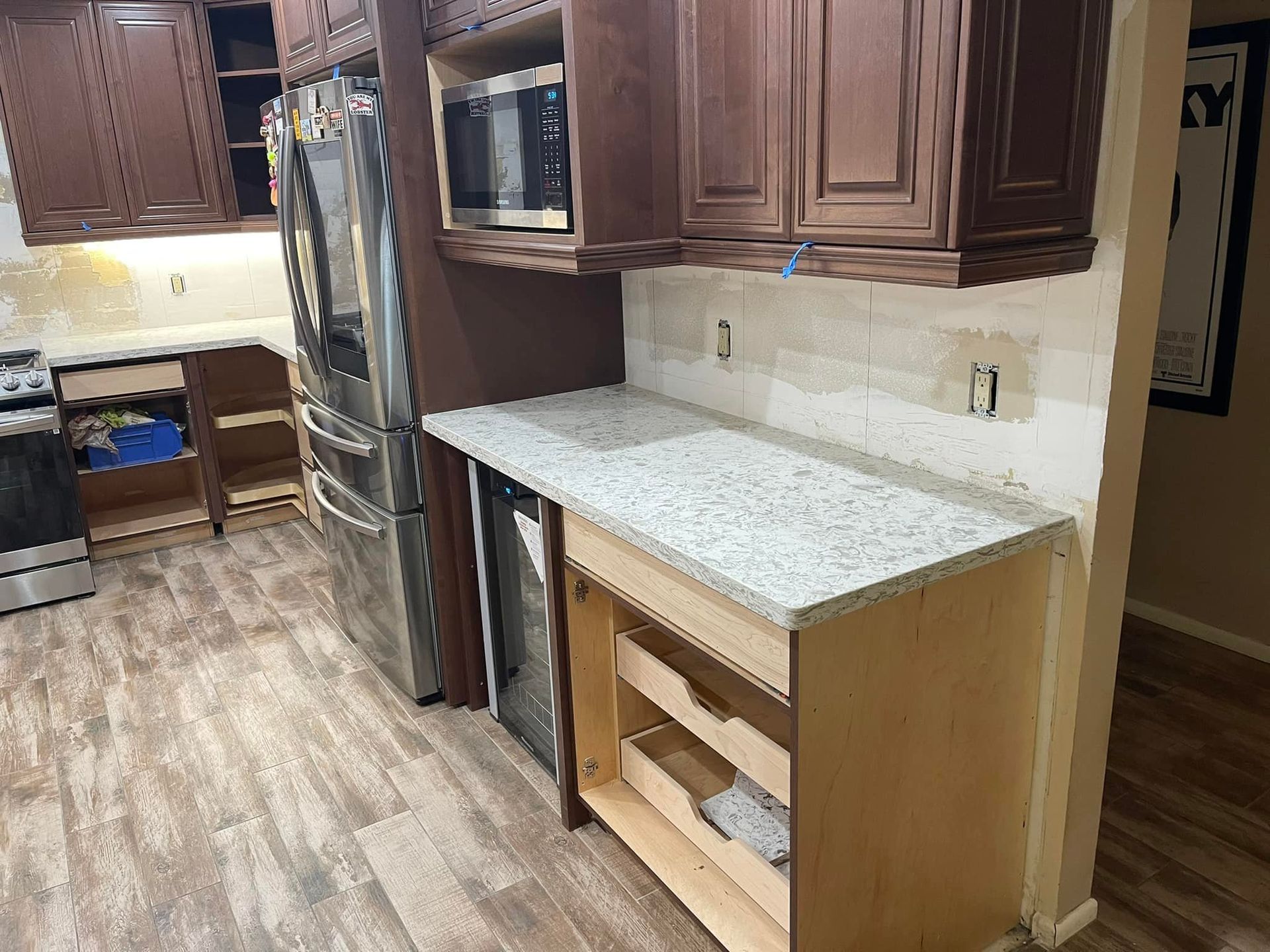 Kitchen renovation: granite countertop, unfinished cabinets, microwave, refrigerator.