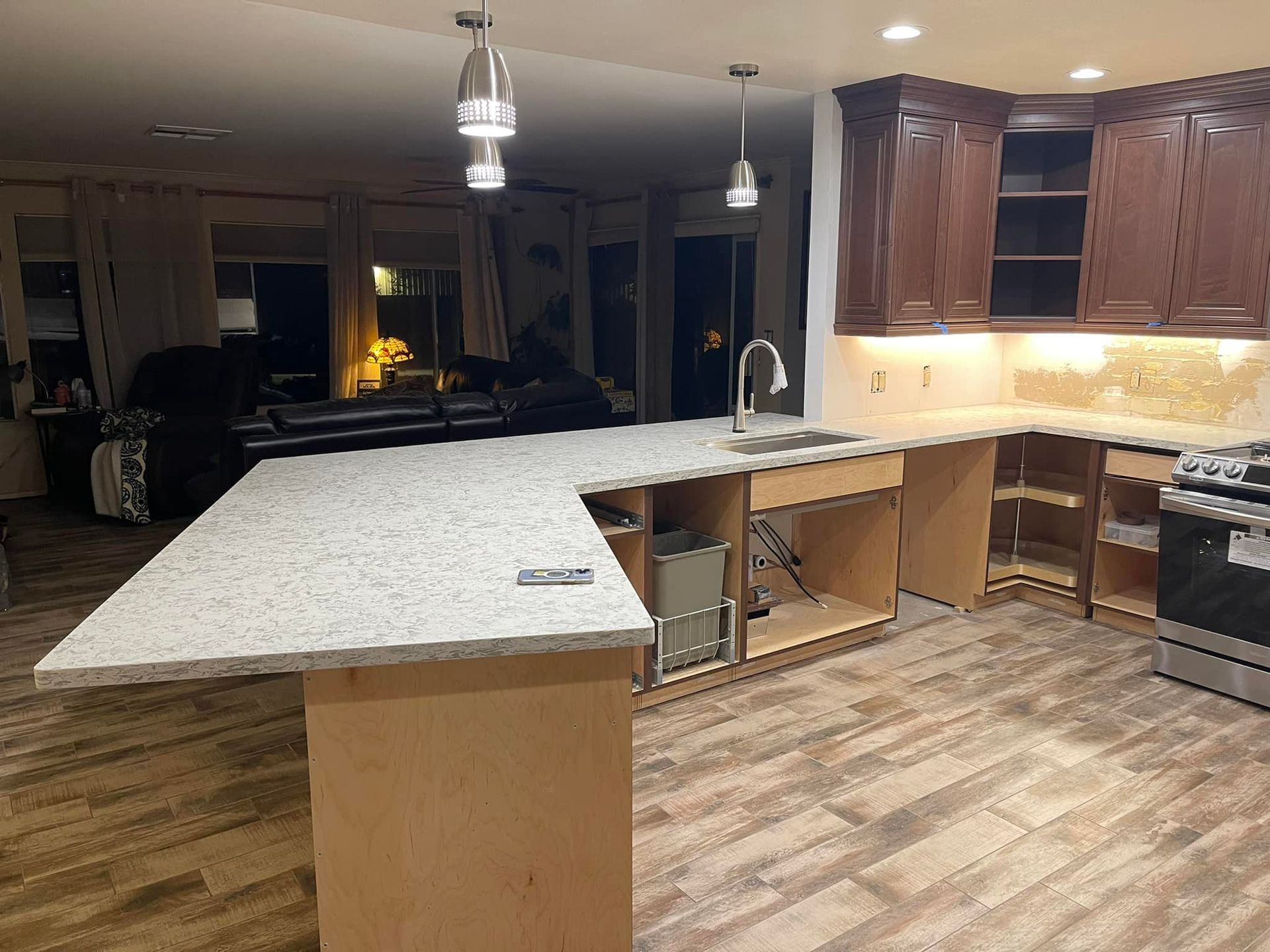 Kitchen renovation with new countertops, cabinets, and exposed plumbing under the island, in a home.