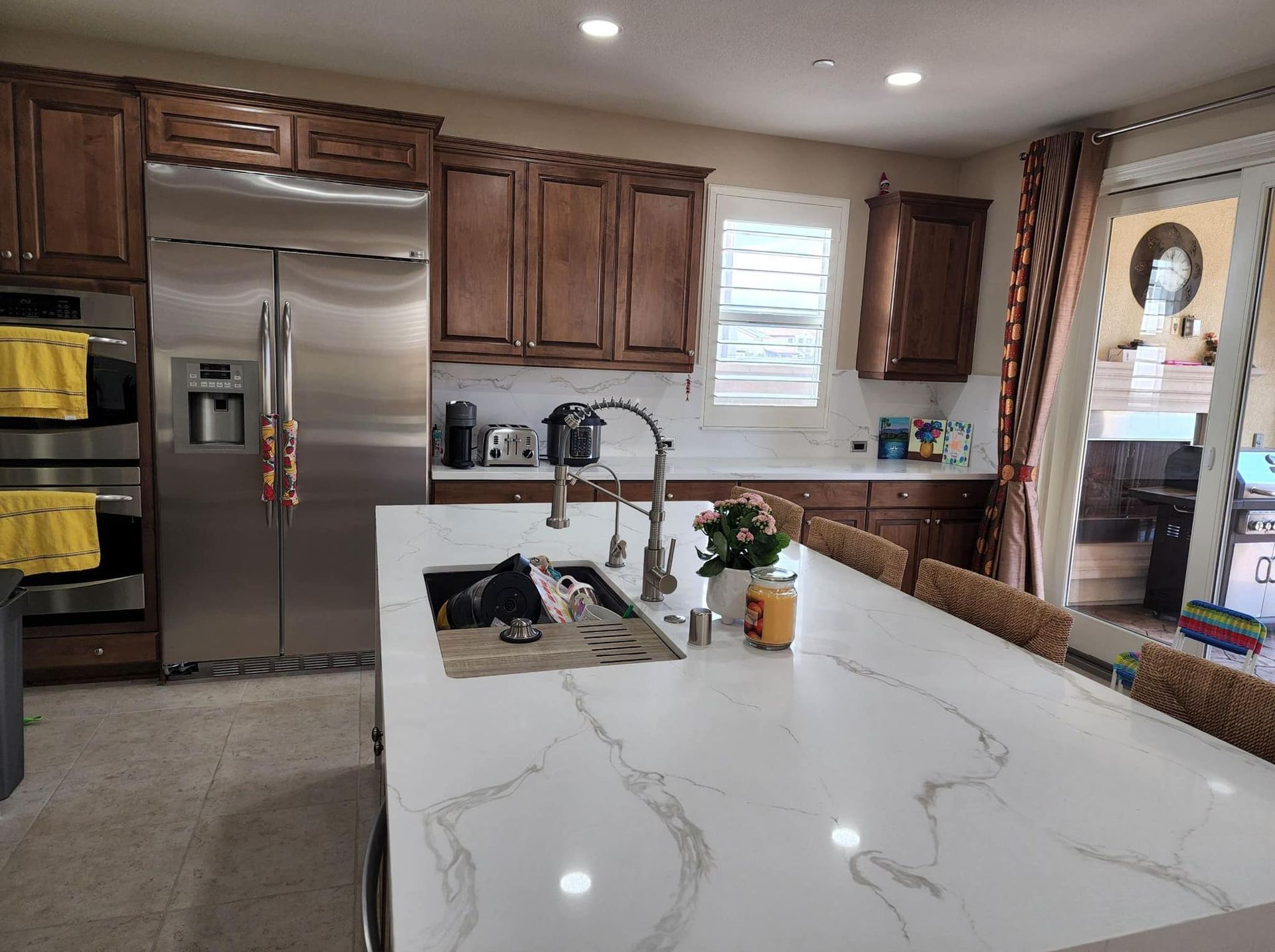 Kitchen with stainless steel appliances, wooden cabinets, and a white countertop island.