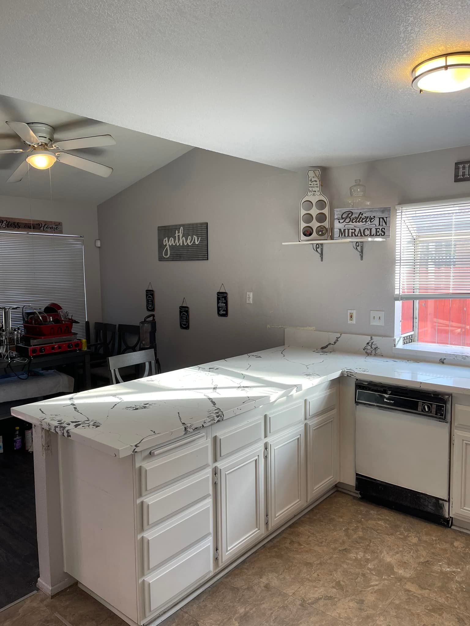Kitchen with white cabinets, quartz countertops, and a window.