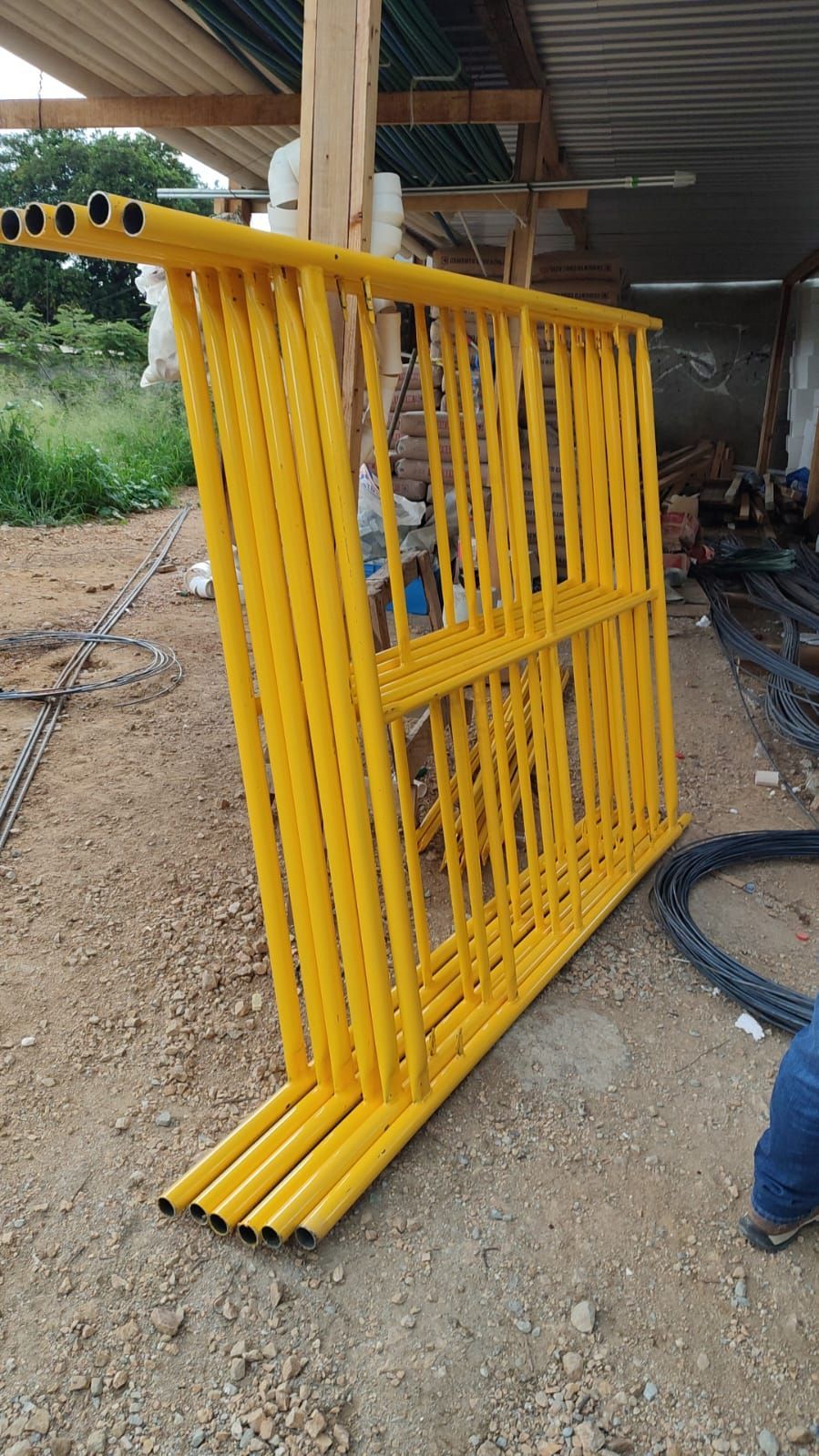 Estructuras de andamio amarillas apiladas sobre una superficie de tierra.