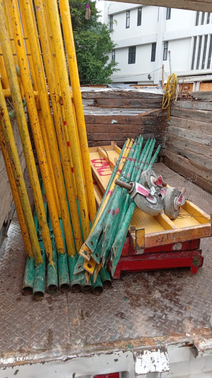 Postes de andamio amarillos y otros equipos de construcción en la caja de un camión.