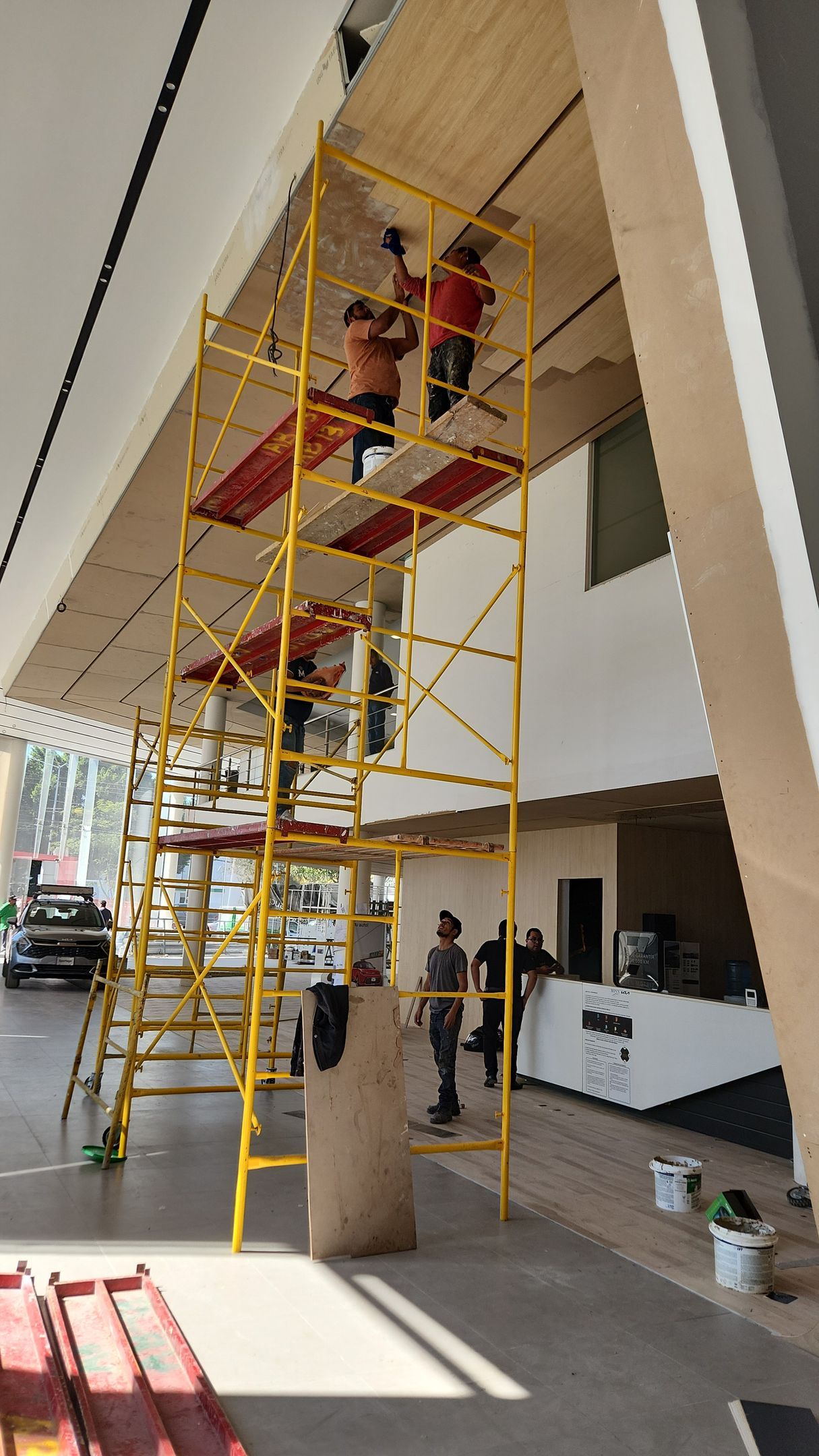 Obreros en un andamio instalando un techo, dentro de un edificio.