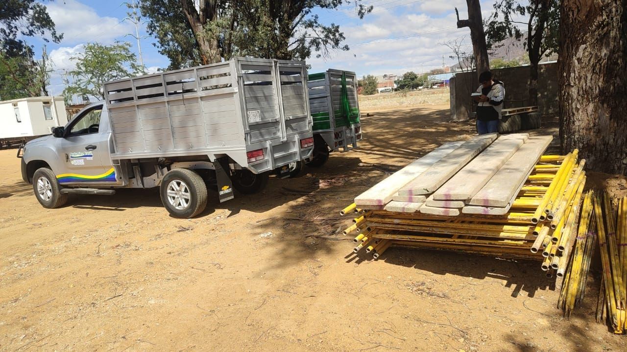 Camiones estacionados junto a tablones de madera; una persona está de pie cerca.