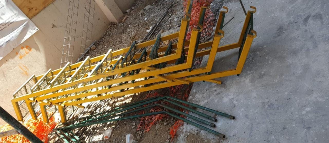 Materiales de construcción metálicos amarillos y verdes sobre una superficie de hormigón.