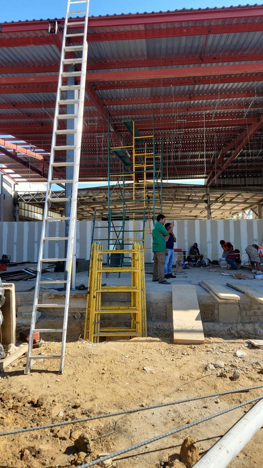 Obra en construcción: Escalera, andamios y obreros dentro de un edificio.