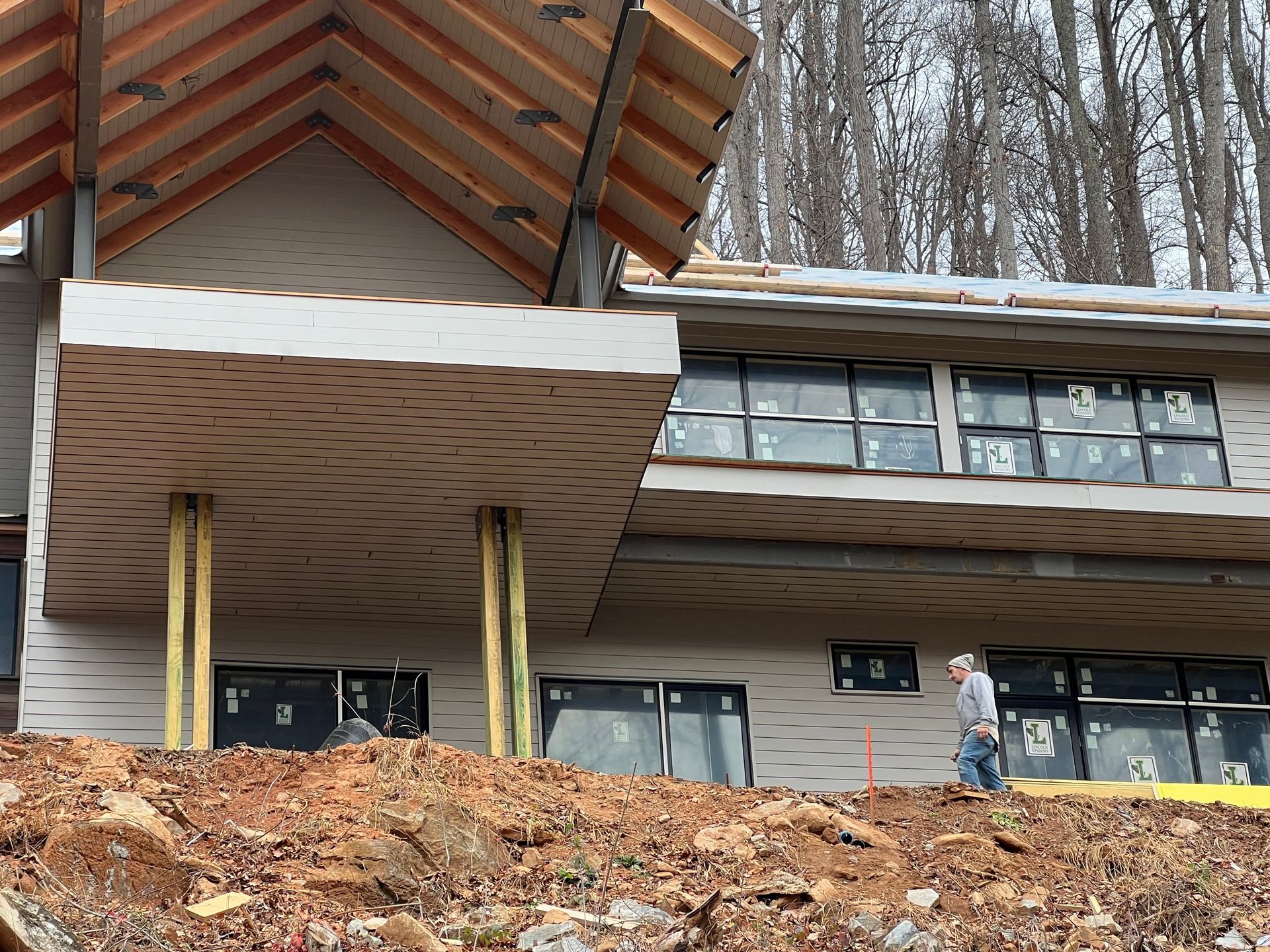 A man is walking in front of a house under construction