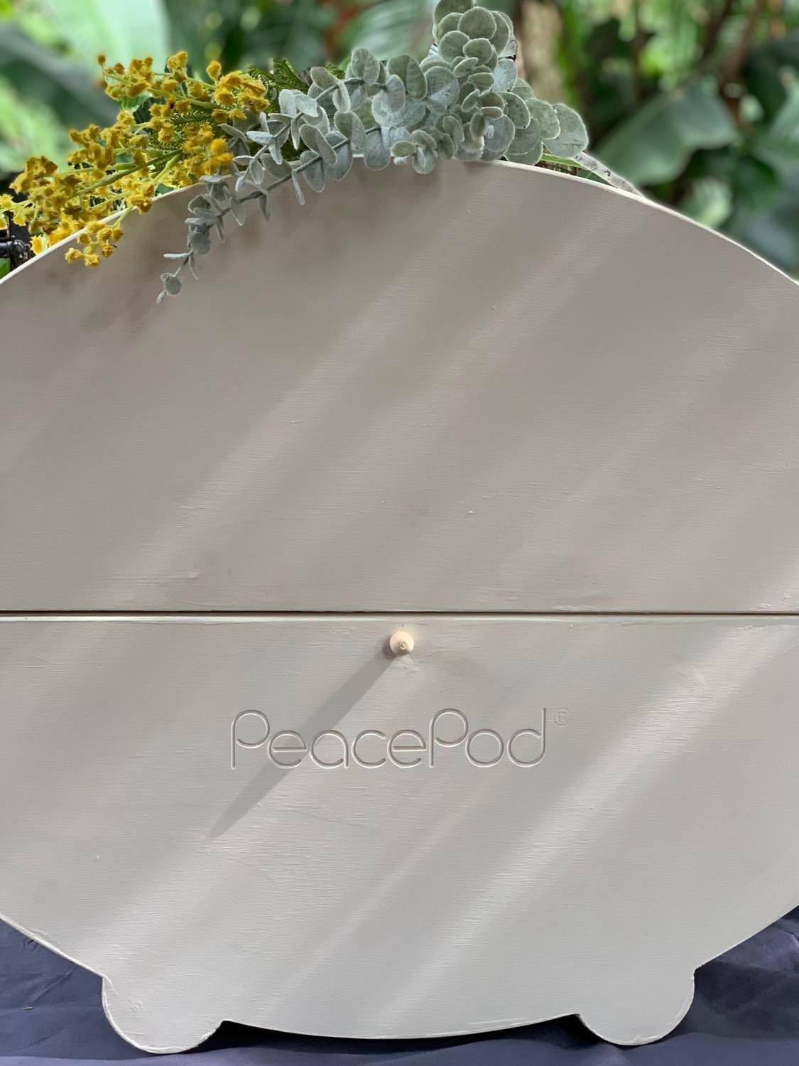 A white coffin with flowers on top of it is sitting on a table.