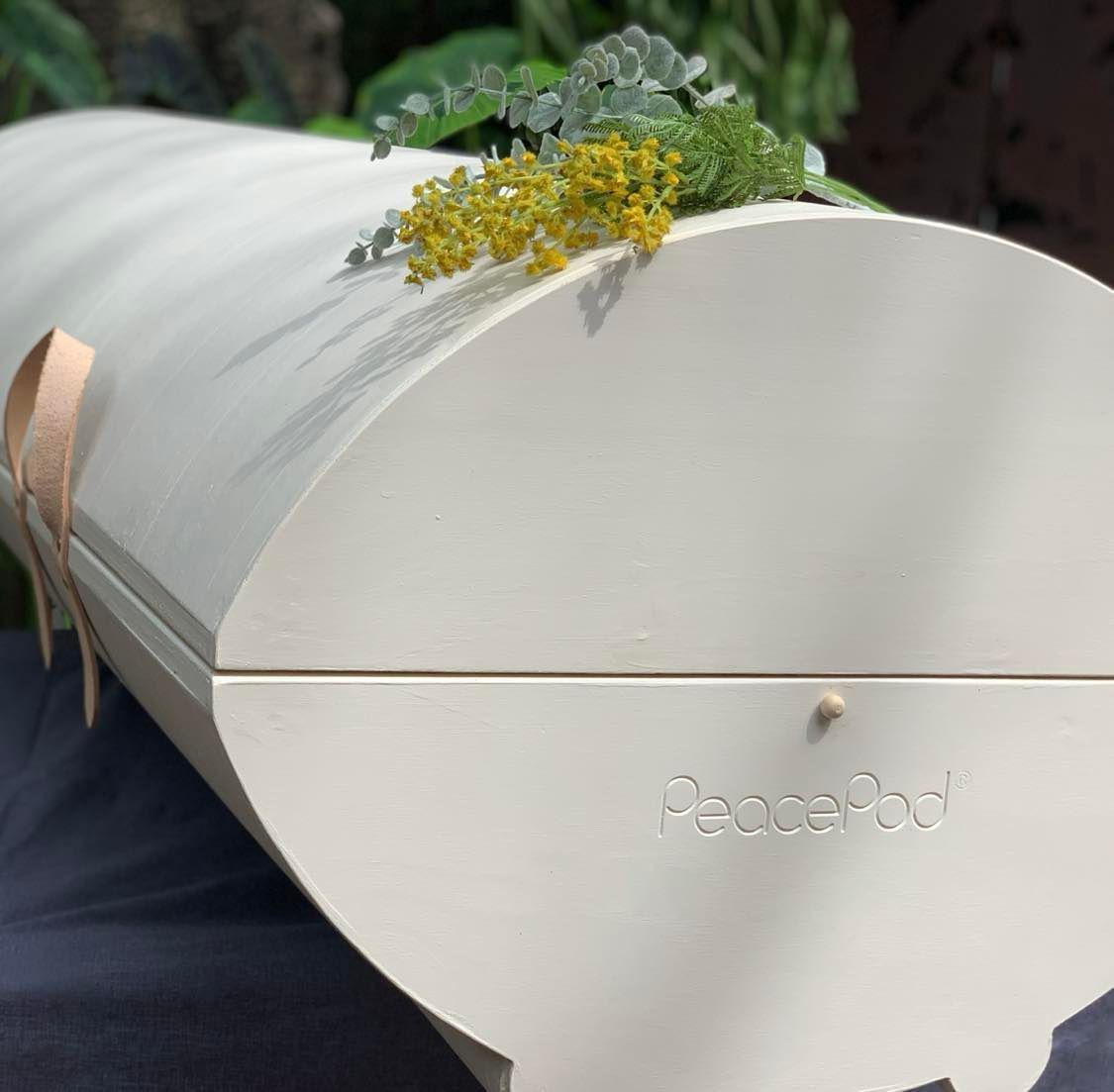 A white coffin with flowers on top of it is sitting on a table.