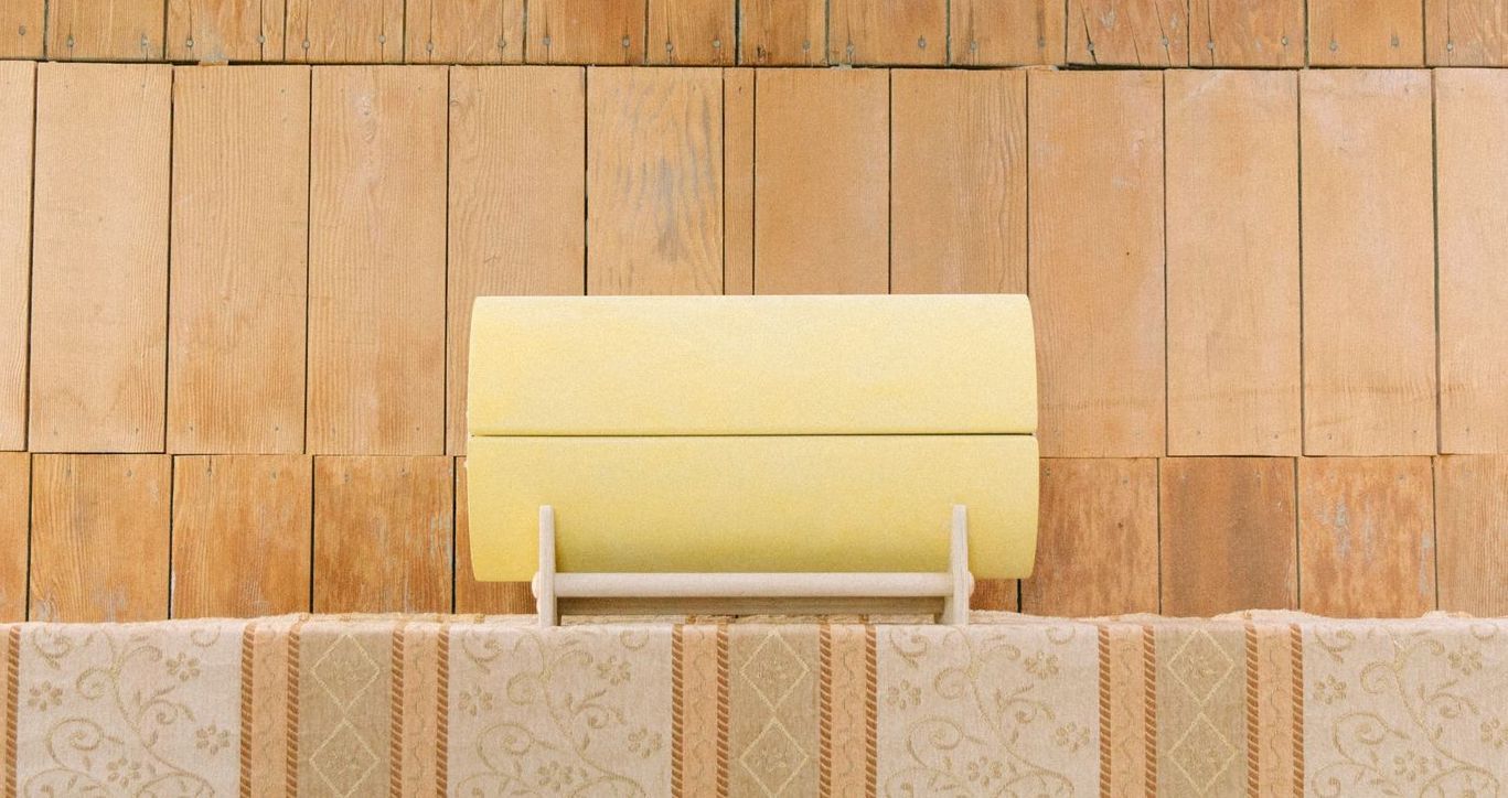 A yellow infant casket is sitting on top of a wooden table.