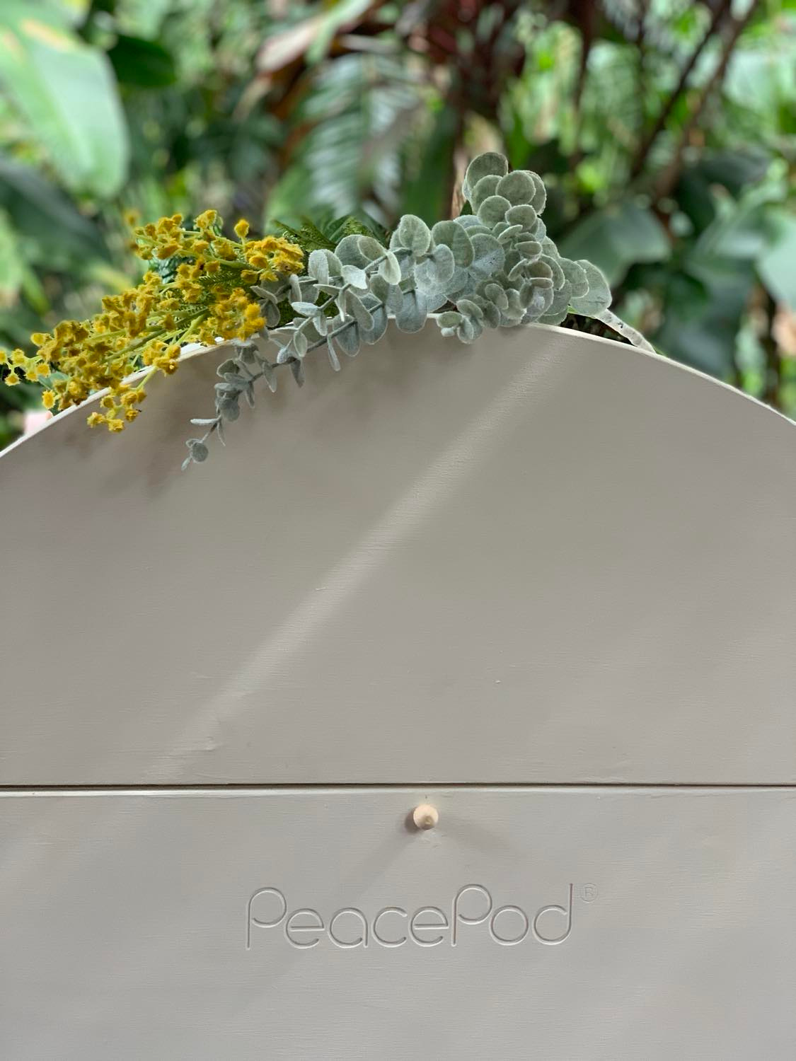 A close up of a PeacePod casket with flowers on top of it.