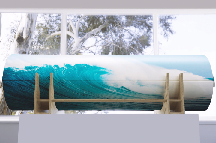A coffin with a picture of a wave on it is on display in front of a window.