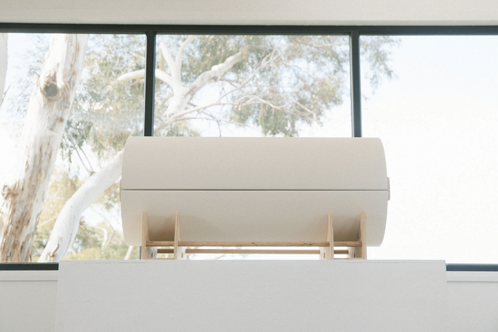 A white infant casket is sitting in front of a large window.