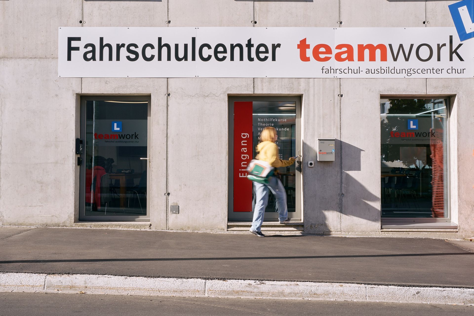 eine Frau geht in das Teamwork-Fahrschulzentrum in Chur