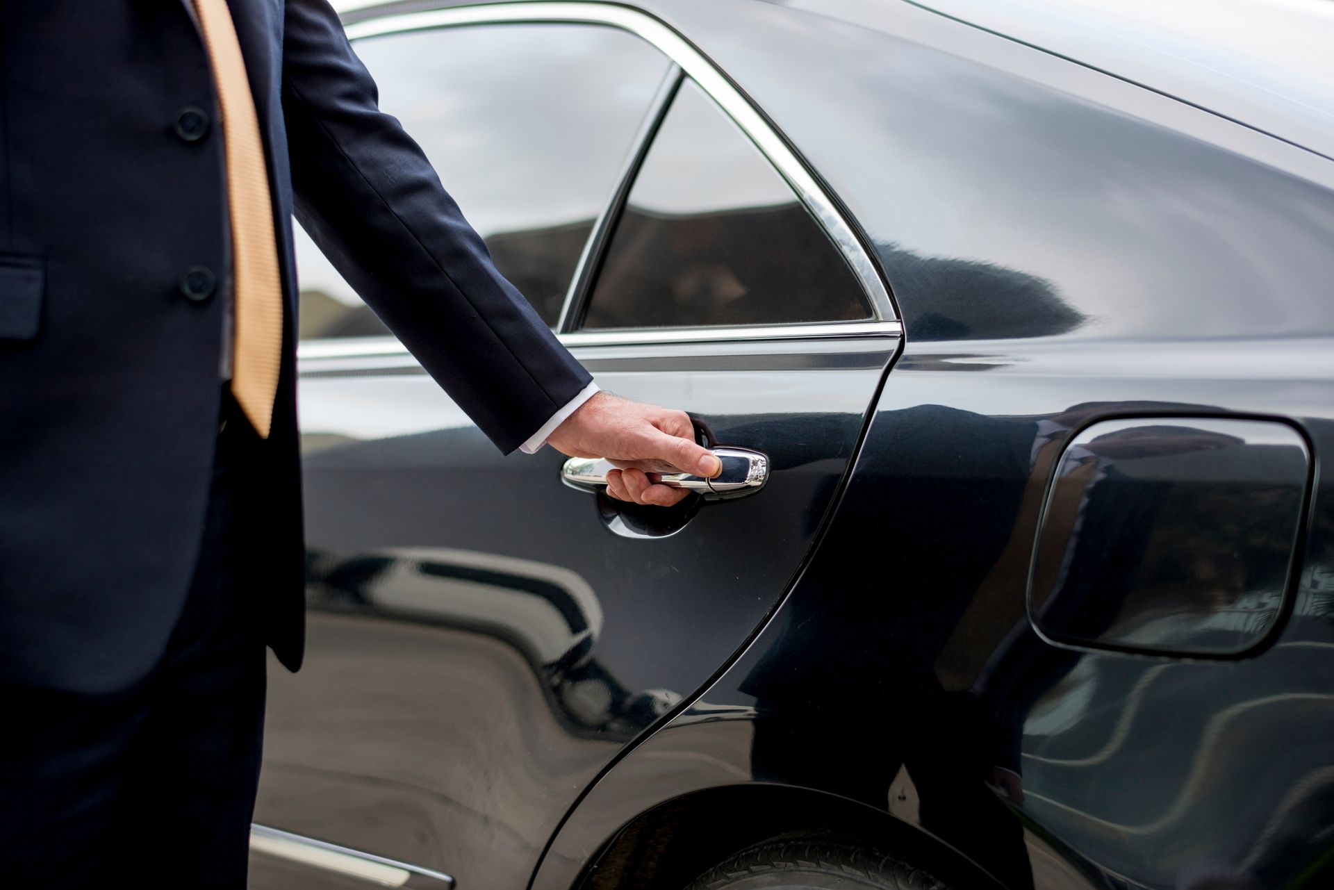 Person opening the door of a black car with a key fob, close-up side view