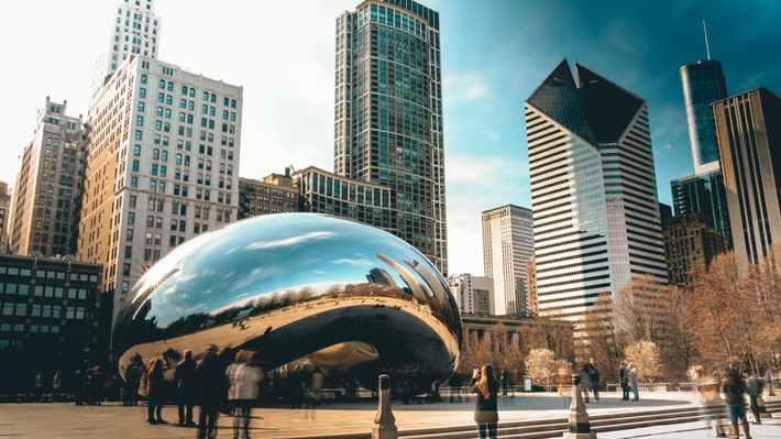 A group of people are standing in front of a large sculpture in a city.