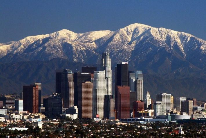 A city skyline with snowy mountains in the background