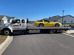 A yellow corvette is being towed by a tow truck.