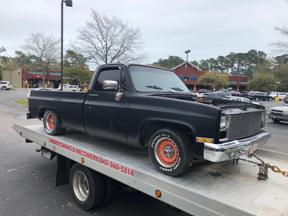 A black truck is sitting on top of a tow truck.