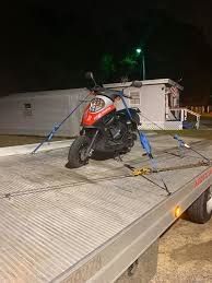 A scooter is sitting on top of a tow truck.