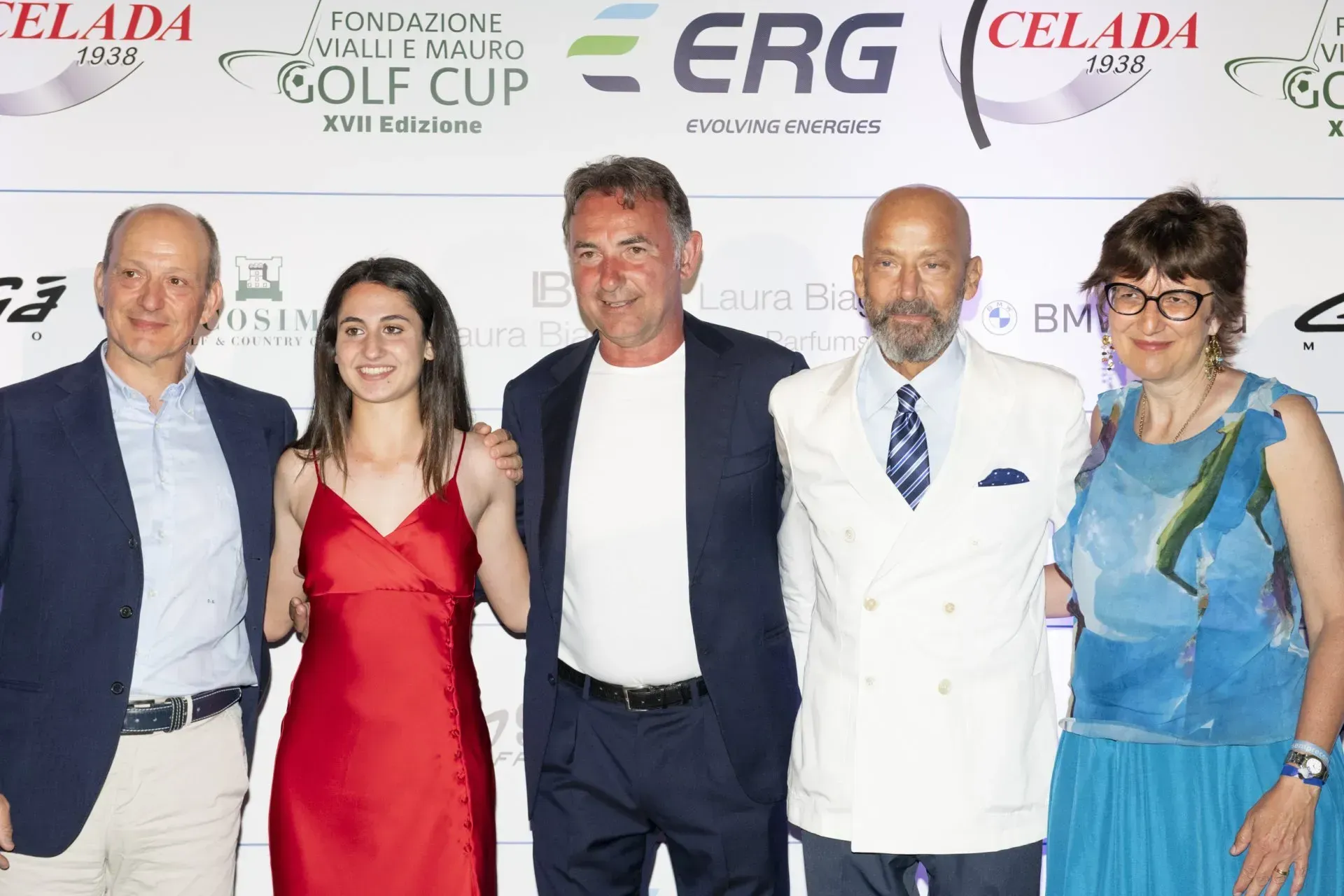 Cinque persone posano a un evento. Sono in piedi, vicine l'una all'altra. L'evento è a tema golfistico.