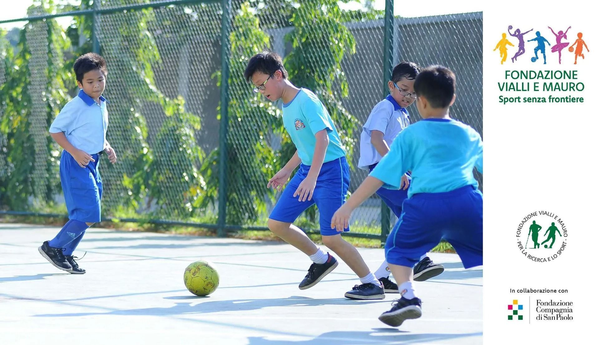 Ragazzi in uniforme blu che giocano a calcio all'aperto.