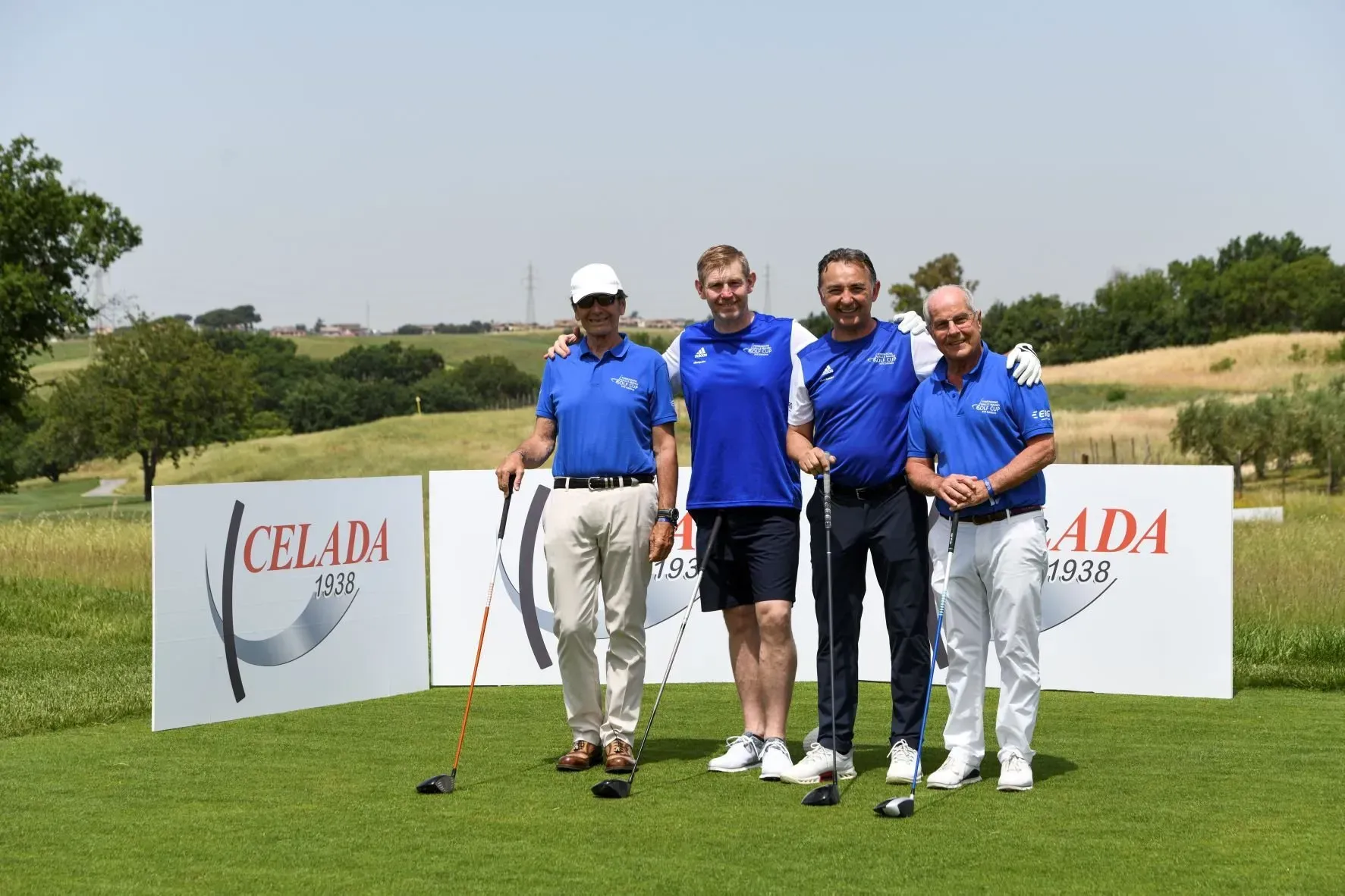 Quattro uomini in camicia blu posano su un campo da golf, con i loghi di Celada sullo sfondo.