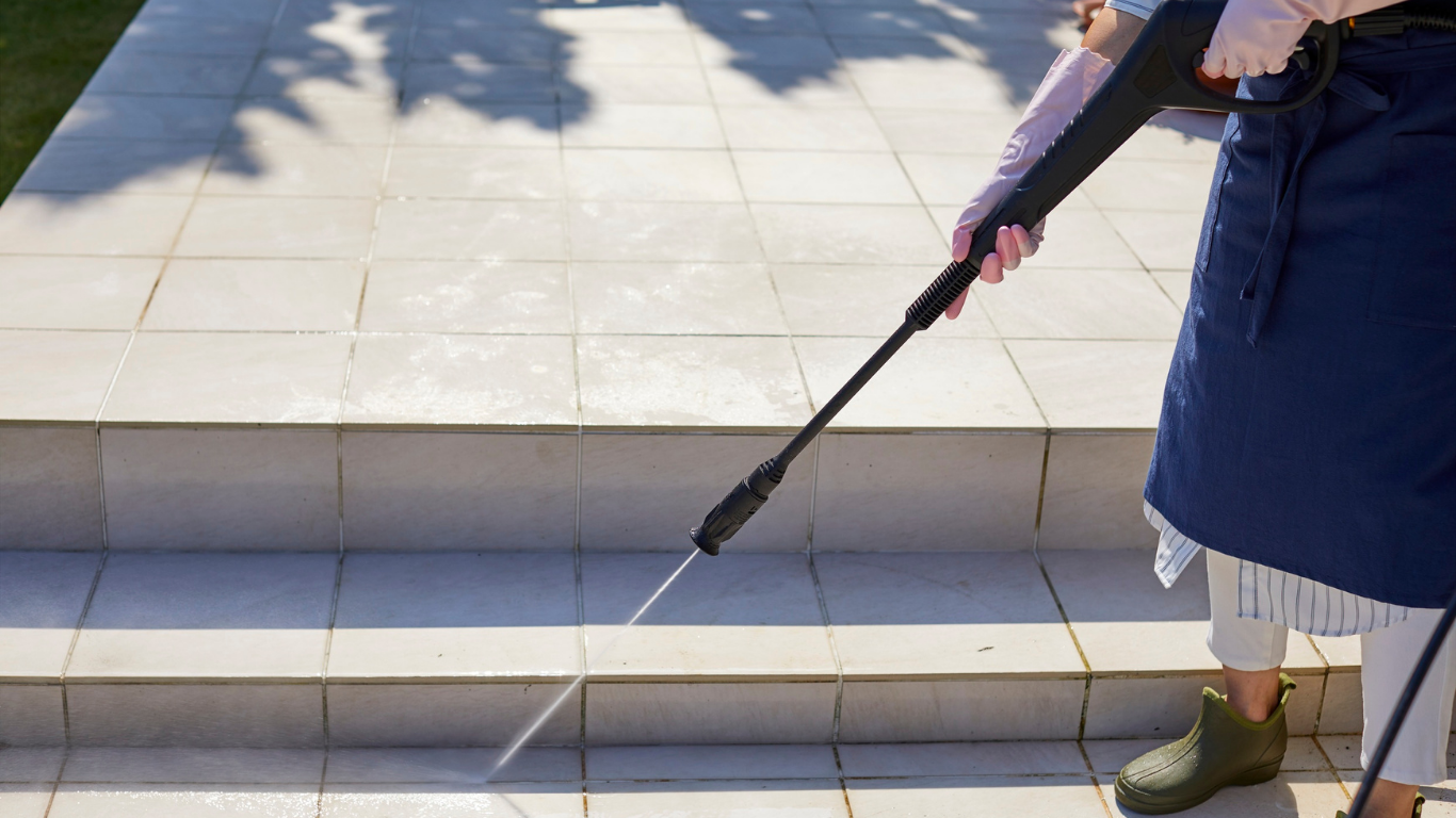 Person pressure washing tiled steps.