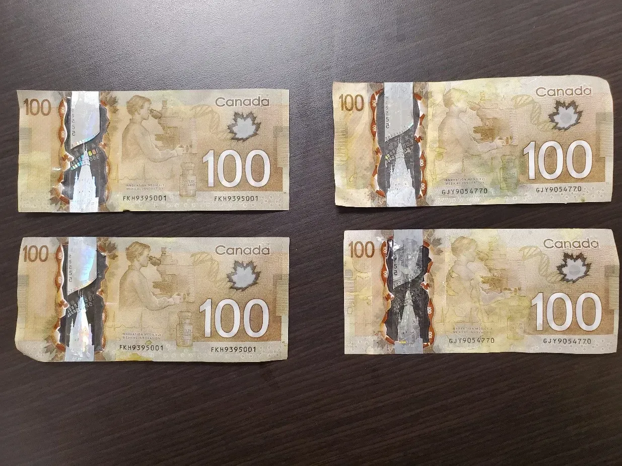 Four canadian 100 dollar bills are sitting on a table.