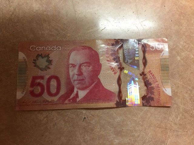 A canadian 50 dollar bill is laying on a table.