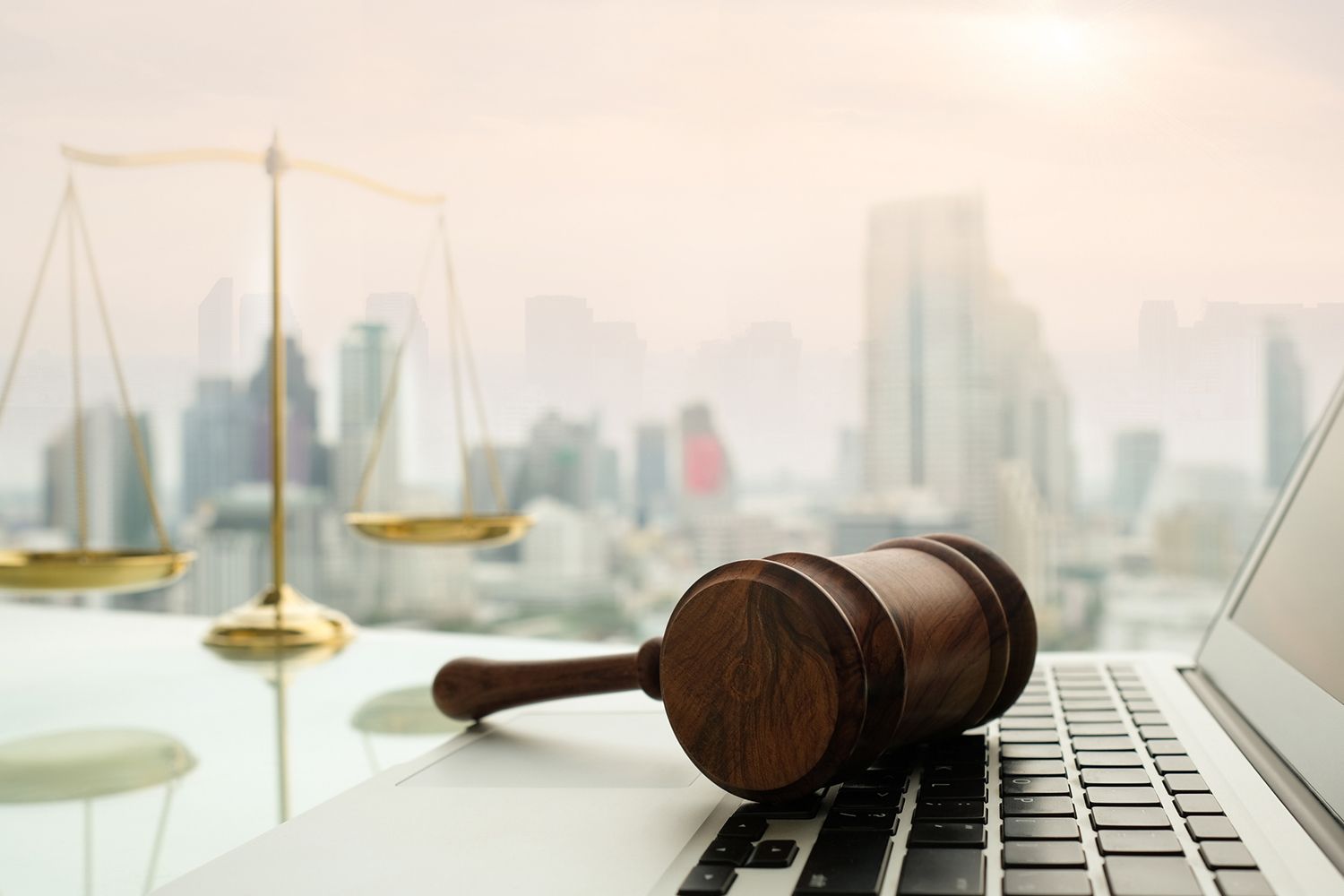 Wooden gavel on laptop, showcasing criminal lawyer work with scales of justice background.