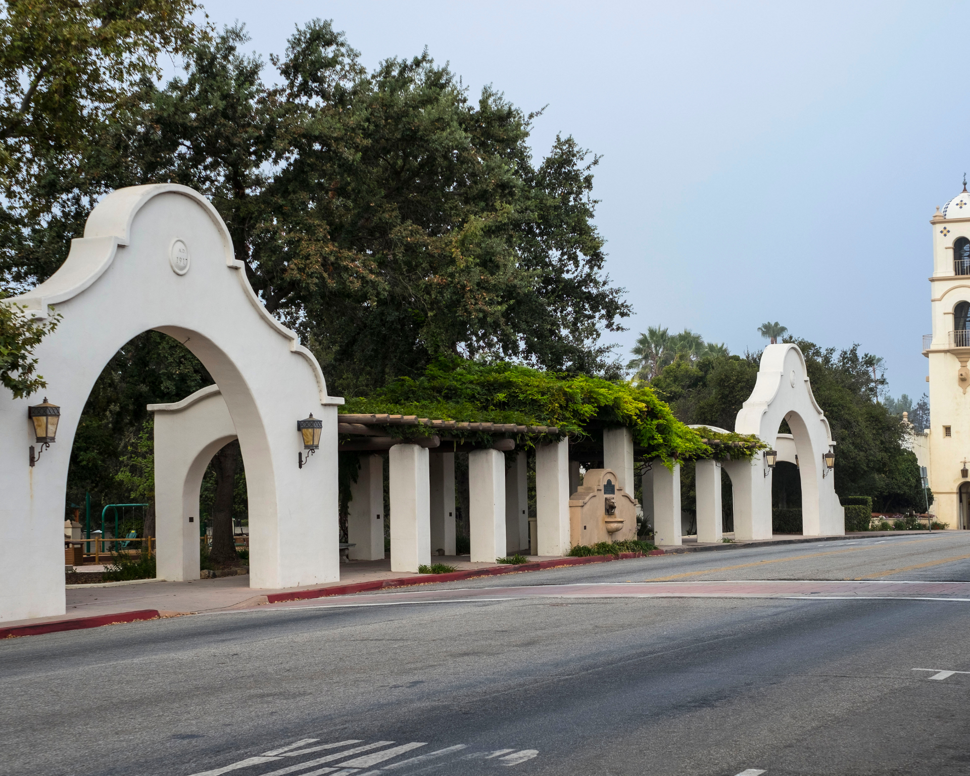 A white archway with a bell tower in the background
