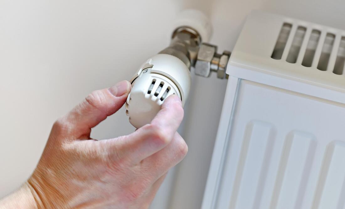 A person is adjusting a thermostat on a radiator.