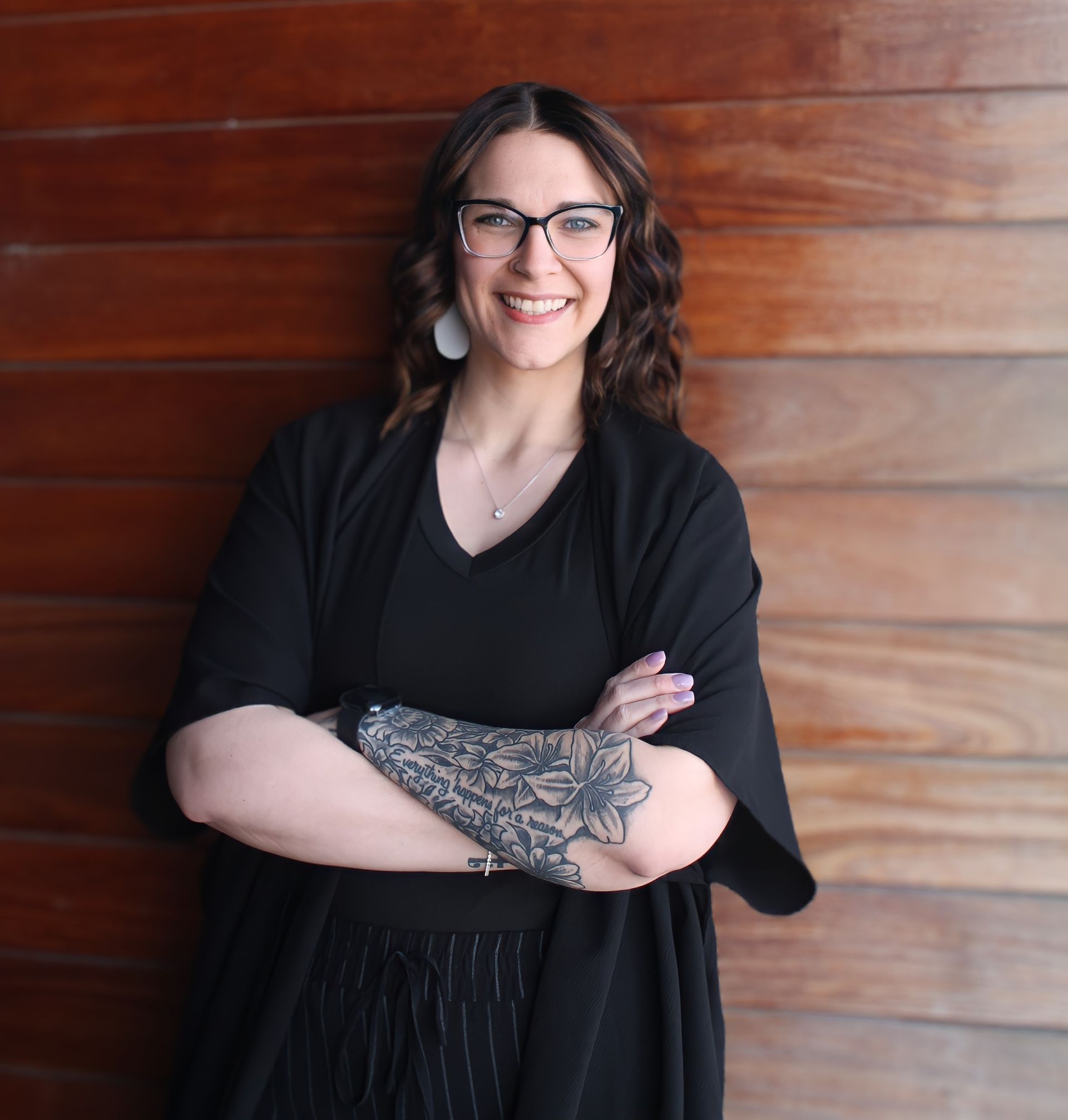 A woman with glasses and a tattoo on her arm
