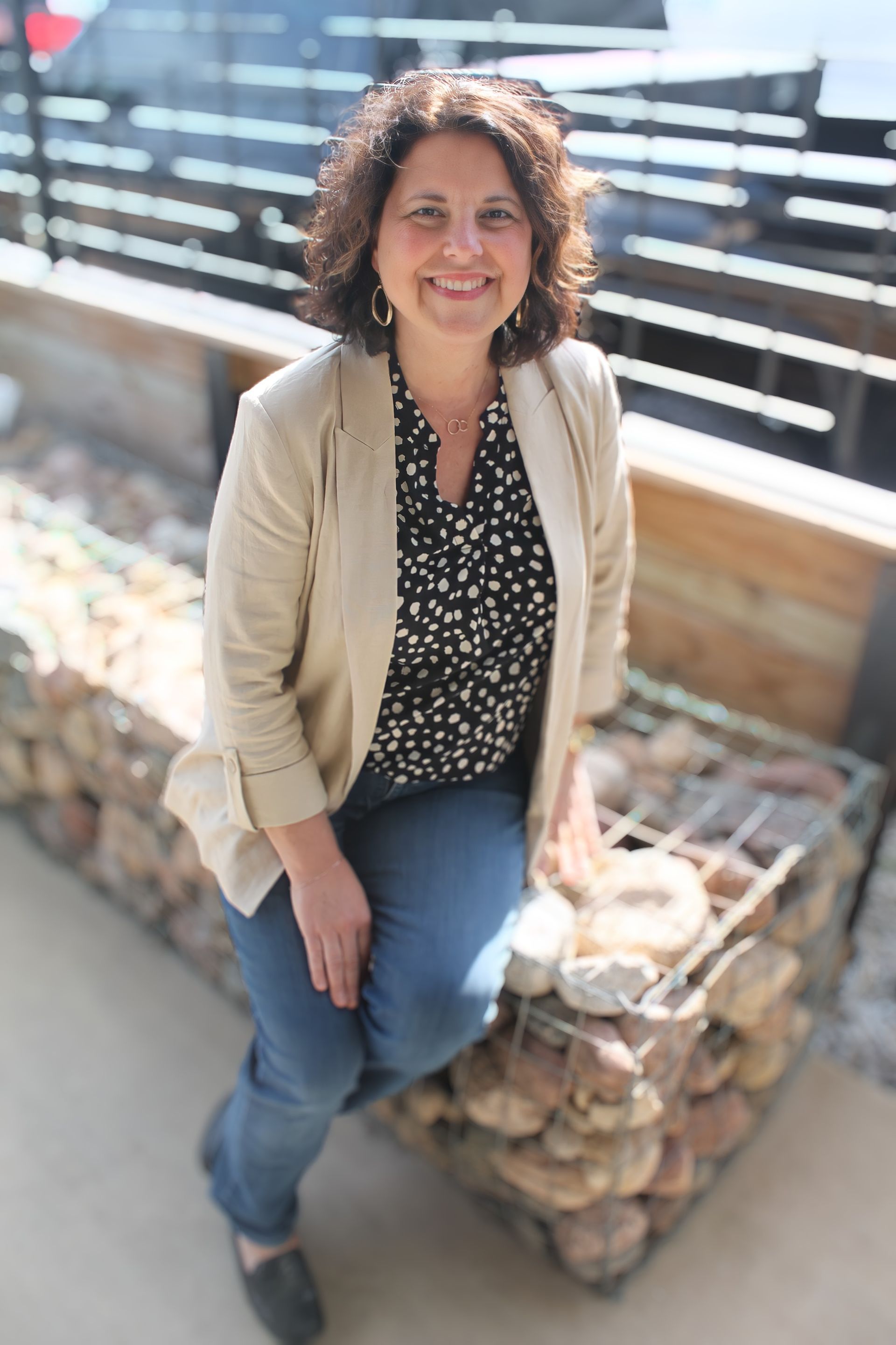 A woman is sitting on a pile of rocks and smiling.
