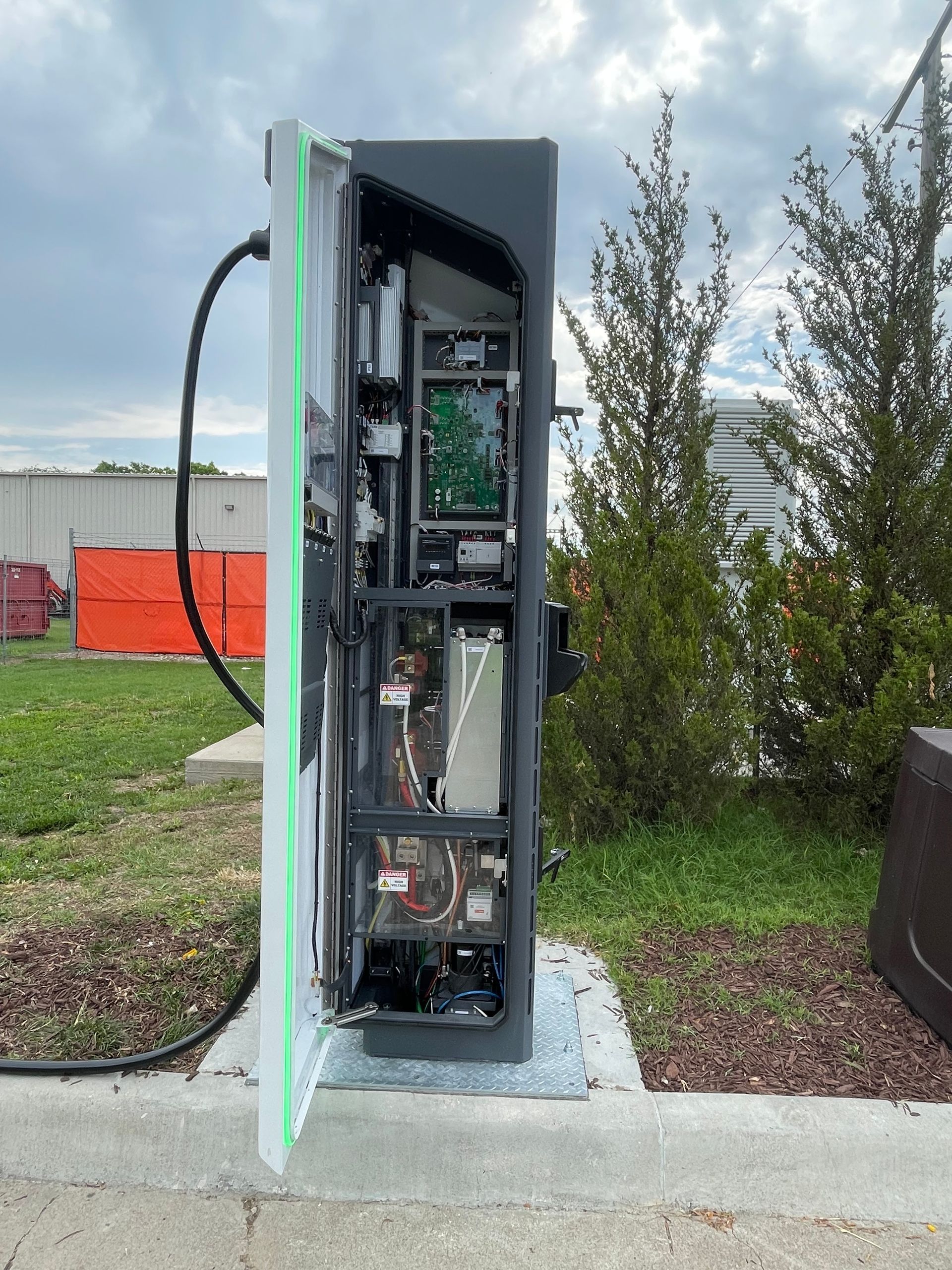 Open electrical panel cabinet outdoors with exposed wiring and components on a concrete base.