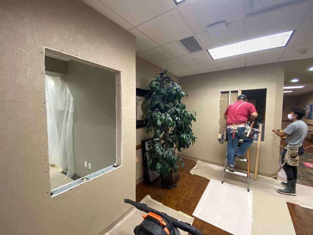 Two men are working on a window in a room.
