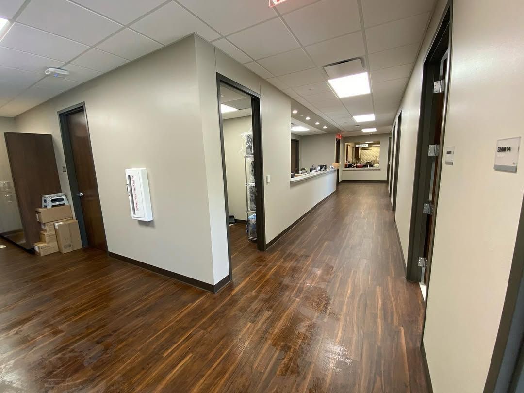 A long hallway with wooden floors and white walls in an office building.