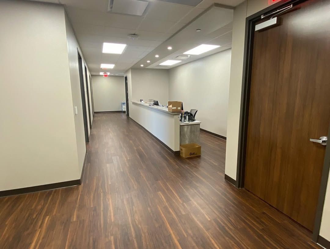 A long hallway with wooden floors and a reception desk.