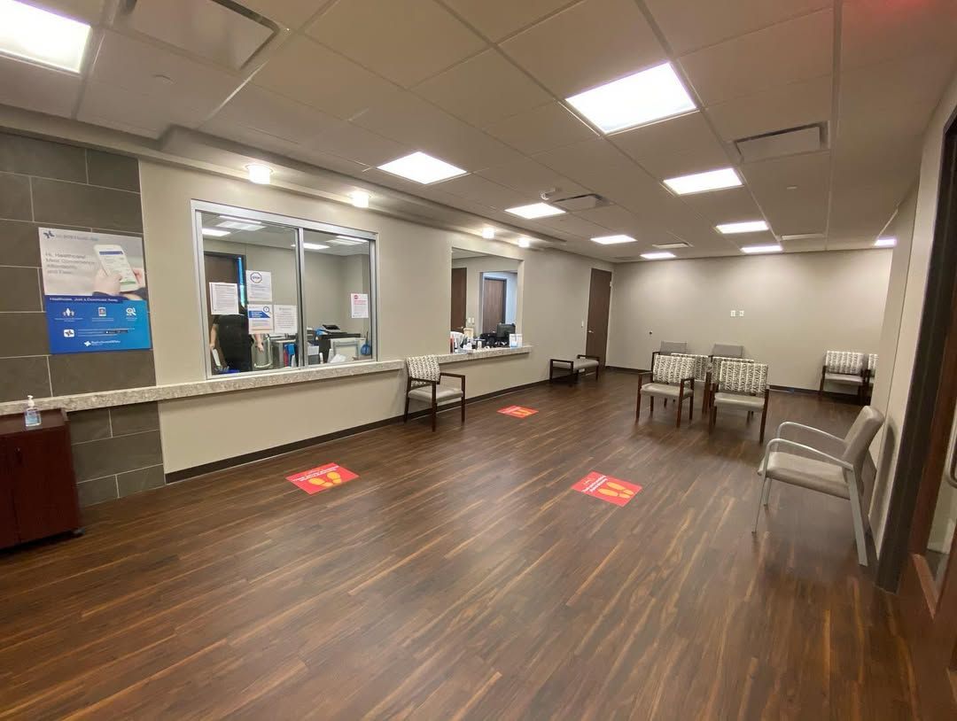 A large room with wooden floors and chairs in a hospital waiting room.